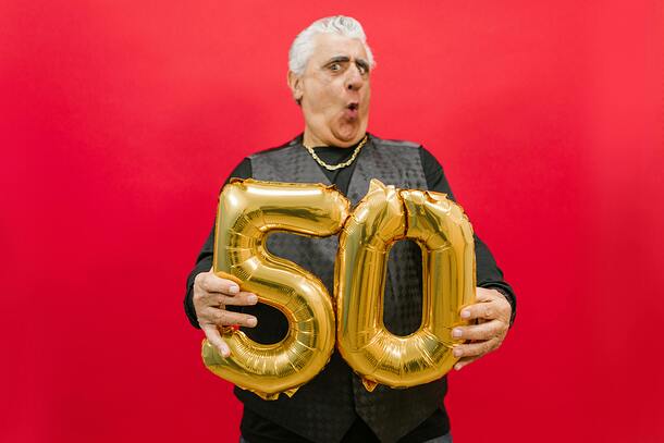 Beeindruckte Person mit Luftballons in Form einer 5 und 0 in der Hand